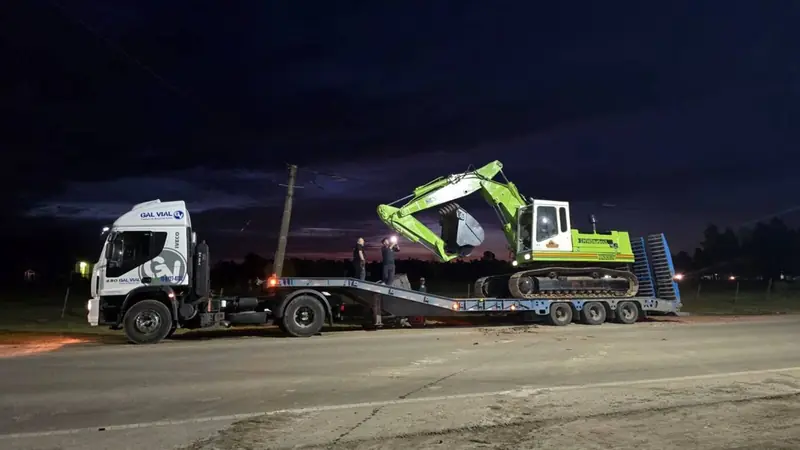 Camión con carretón trasladando una excavadora de noche